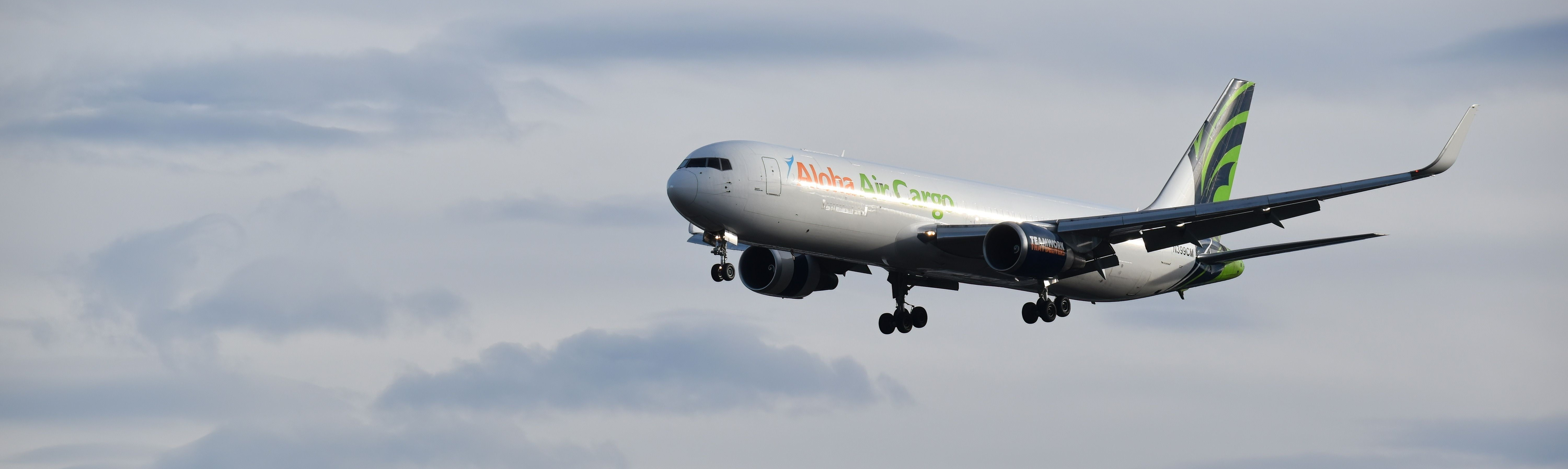 An Aloha Air Cargo plane flying in the sky.