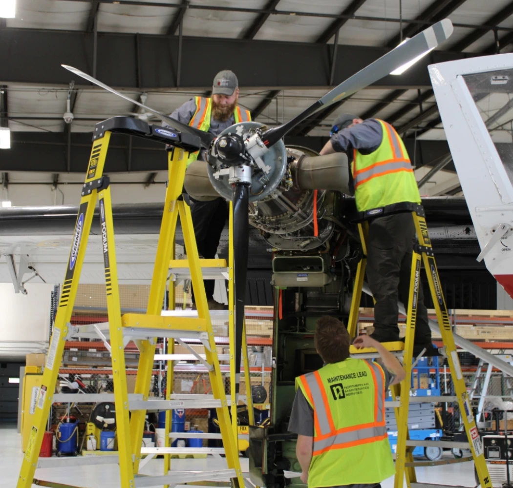 NAMS employees working on the propellor of a plane.