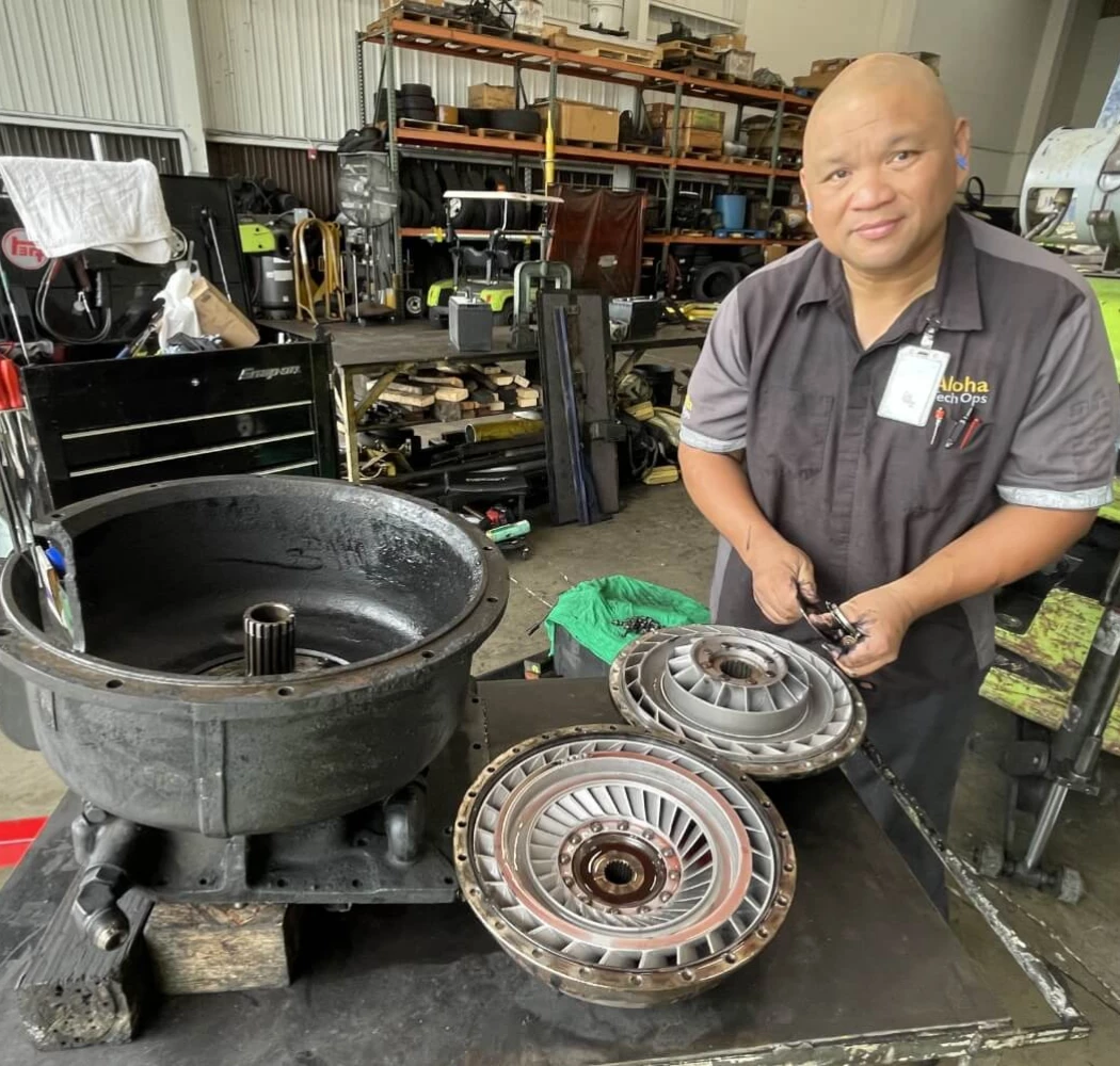 An Aloha Tech Ops employee cleaning a machine's transmission.