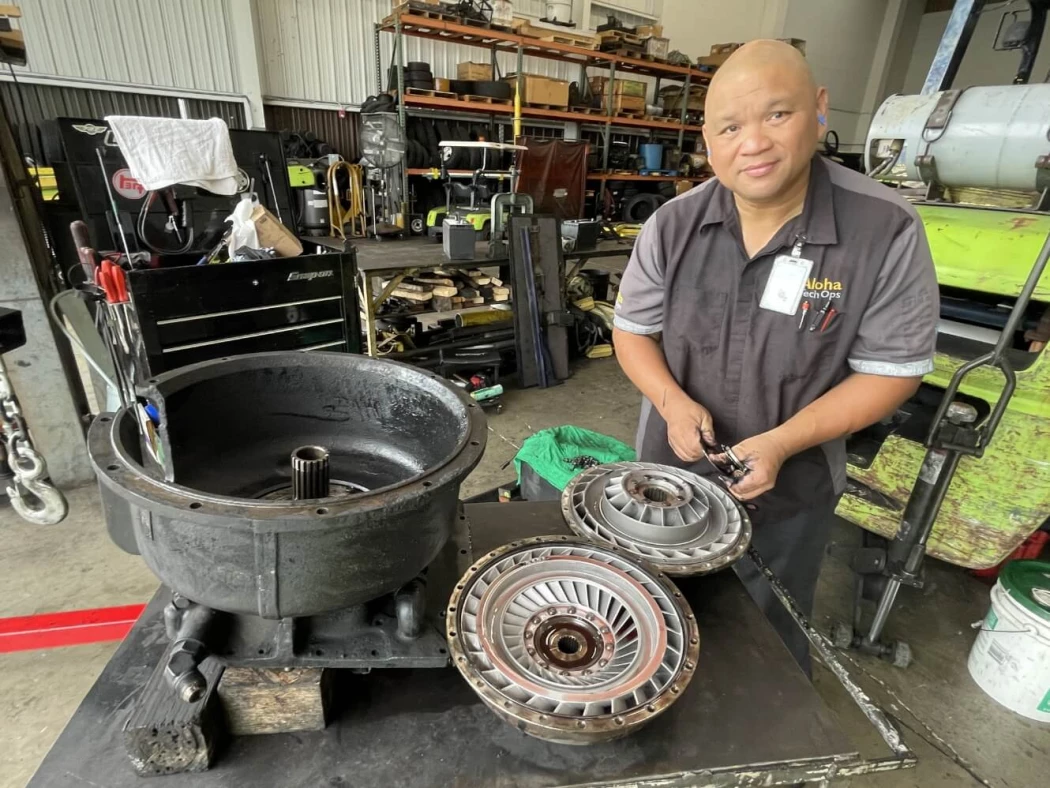 An Aloha Tech Ops employee cleaning a machine's transmission.