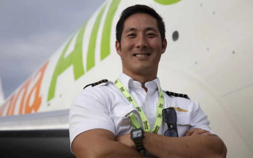 A smiling Aloha Air Cargo pilot standing in front of a plane.