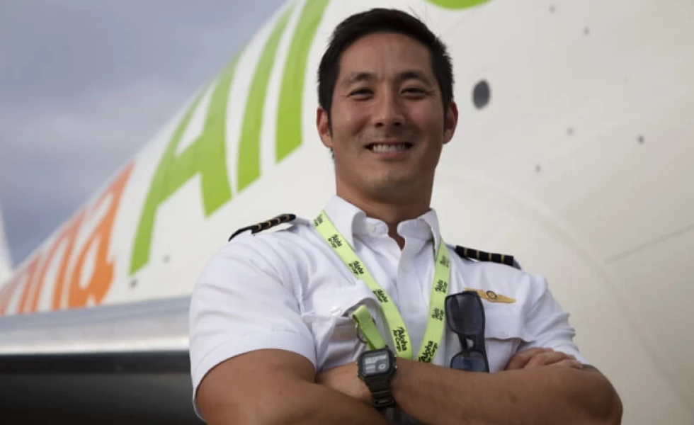 A smiling Aloha Air Cargo pilot standing in front of a plane.