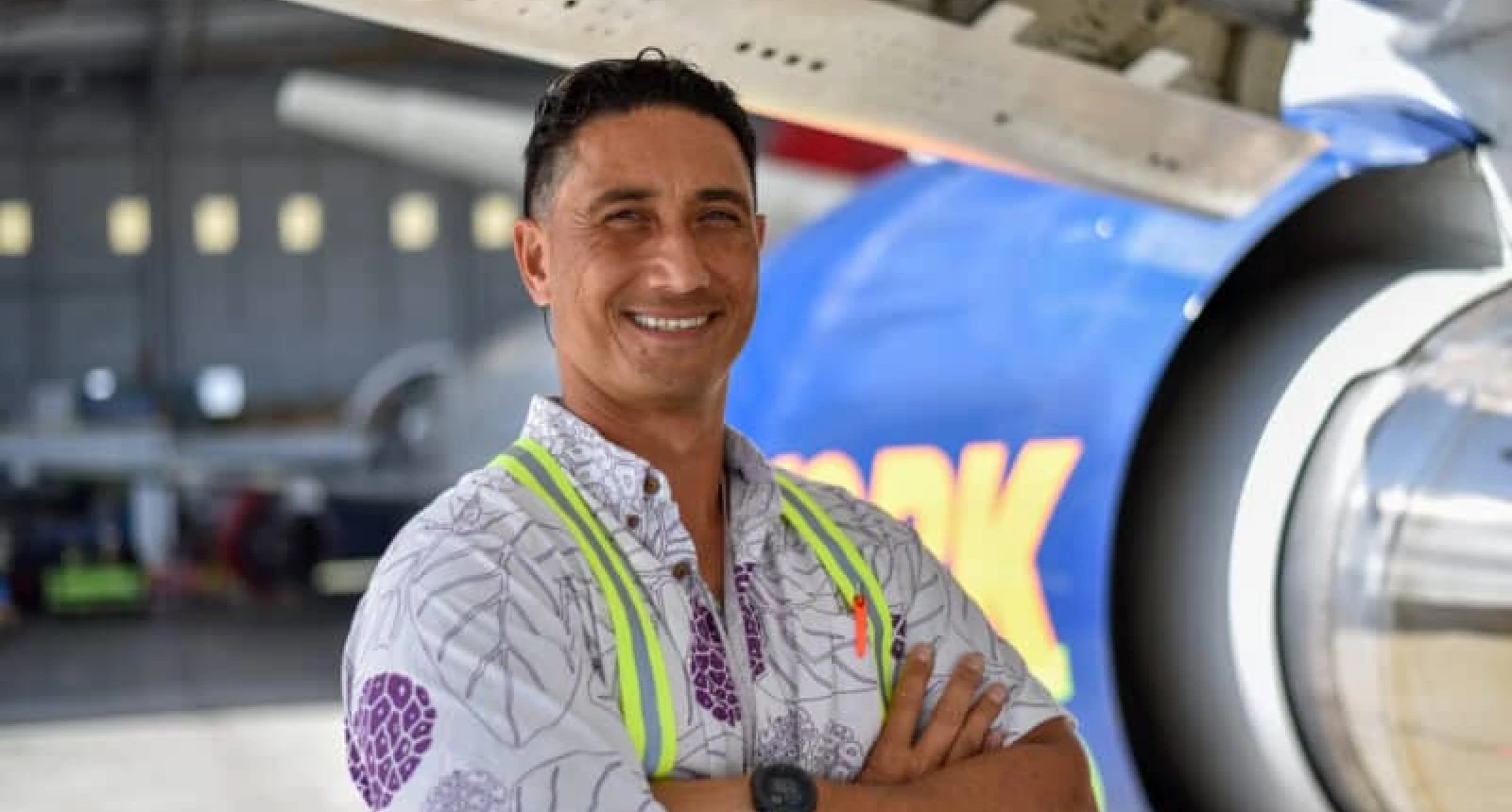 Photo of Aloha Tech Ops employee Mario Mausio standing in front of a plane.