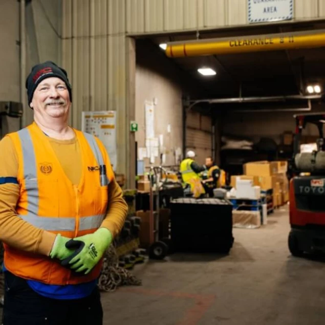 A NAC employee standing in front of the Dangerous Goods department in the warehouse.