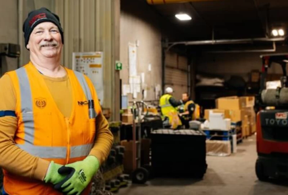 A NAC employee standing in front of the Dangerous Goods department in the warehouse.