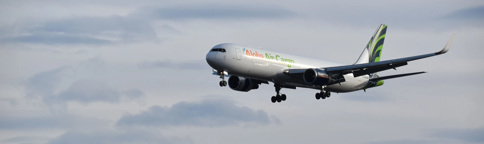 An Aloha Air Cargo plane flying in the sky.