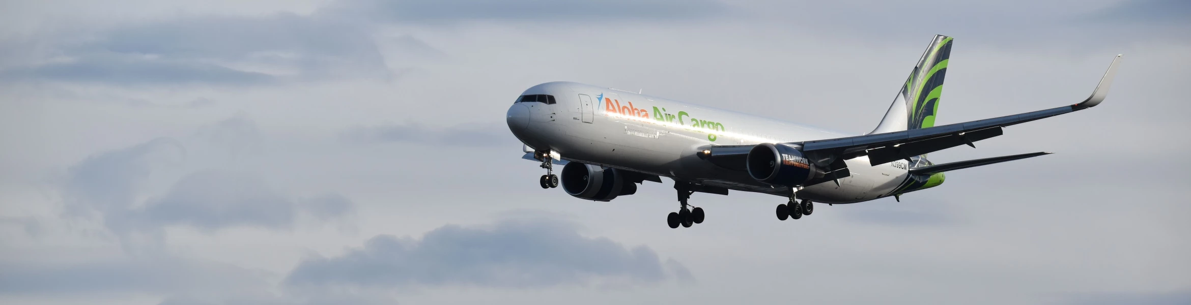 An Aloha Air Cargo plane flying in the sky.