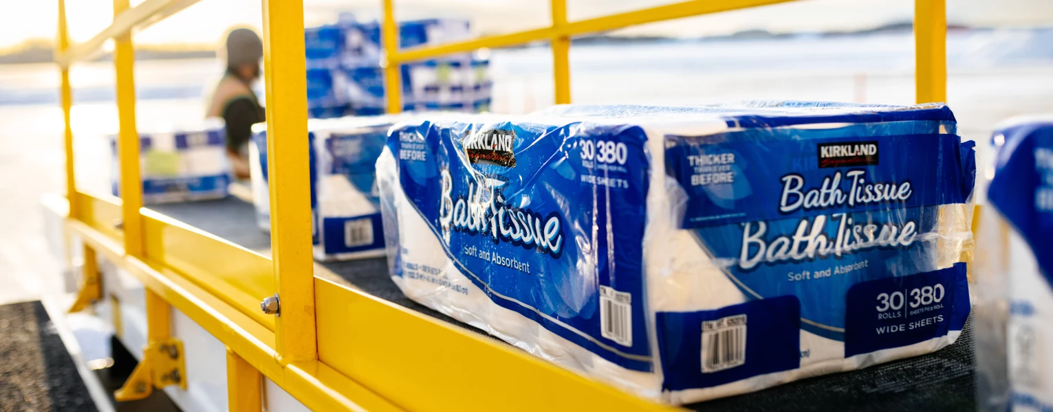 Pallets of bath tissue being loaded onto the conveyor belt arriving into the belly of the aircraft for transport in Alaska.
