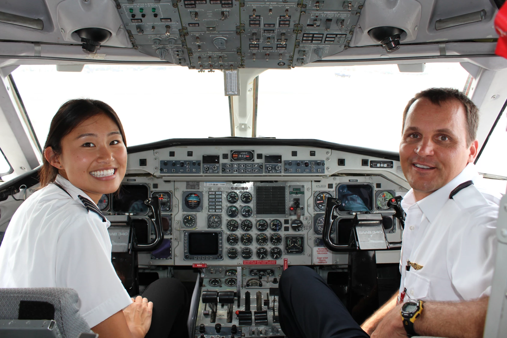 Two Aloha Air Cargo pilots in the plane cockpit, smiling for the camera.