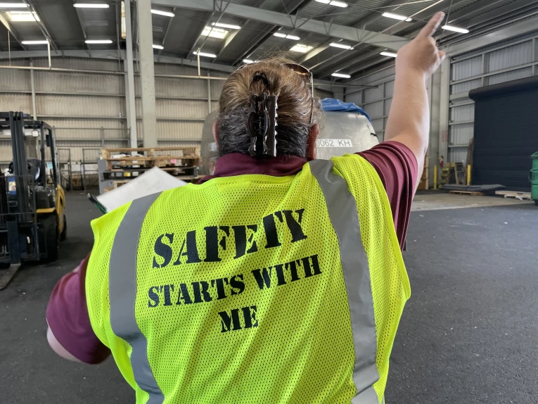 An Aloha Air Cargo employee in the warehouse wearing a yellow safety vest that reads, Safety Starts With Me.