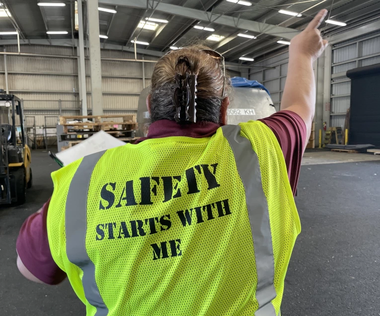 An Aloha Air Cargo employee in the warehouse wearing a yellow safety vest that reads, Safety Starts With Me.